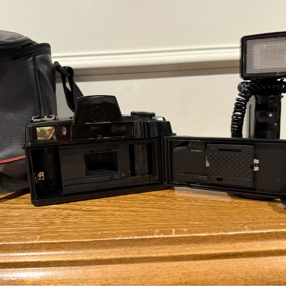 Vintage Canon camera with a flash attachment and carrying case.
